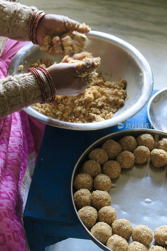 这是印度传统的印度糖果，由身着粉色纱丽的妇女双手制作，til ke ladoo食谱照片，芝麻球，可可粉牛奶，jaggery sugar，印度